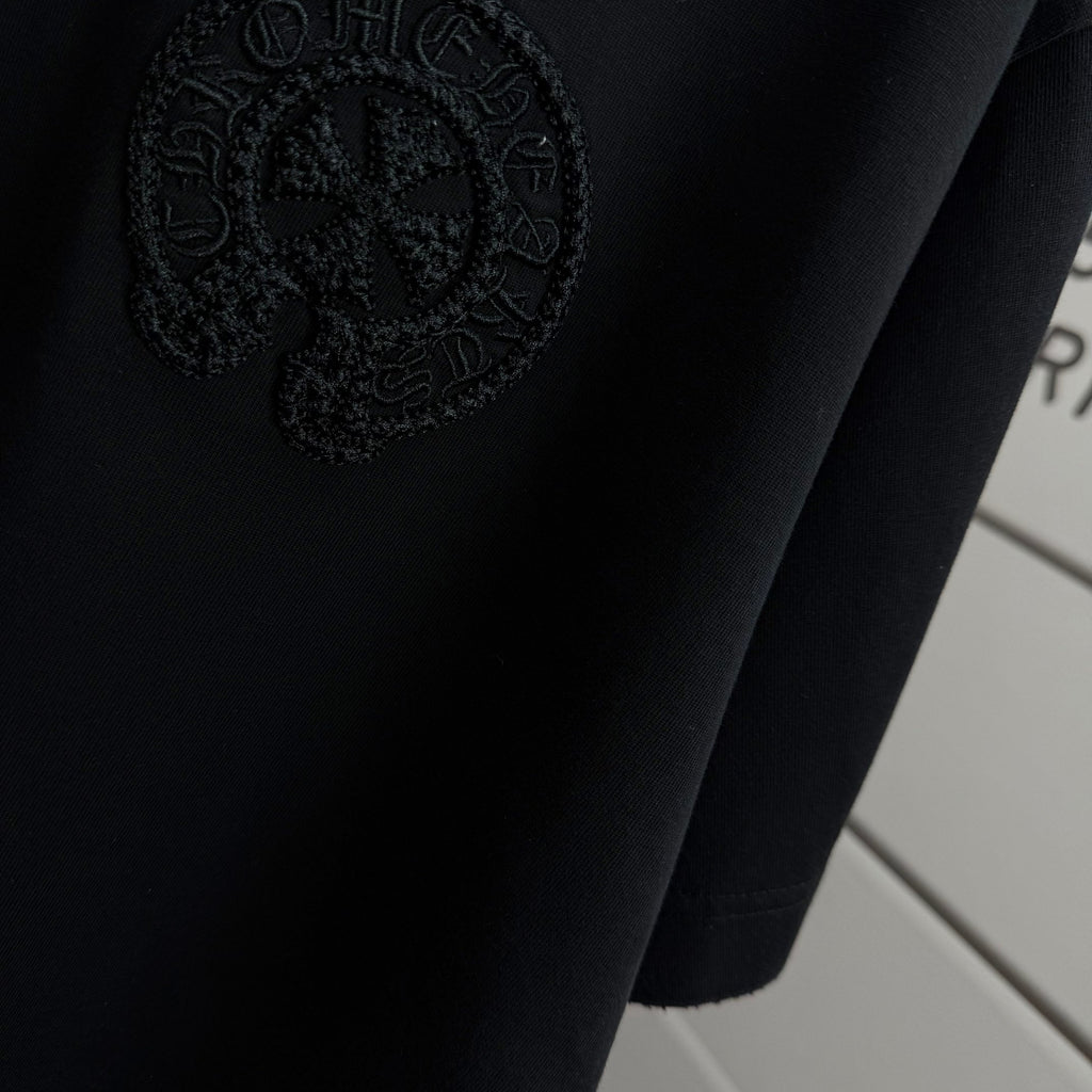 Black short-sleeve T-shirt with embossed circular logo detail near hem