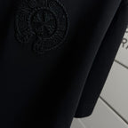 Black short-sleeve T-shirt with embossed circular logo detail near hem