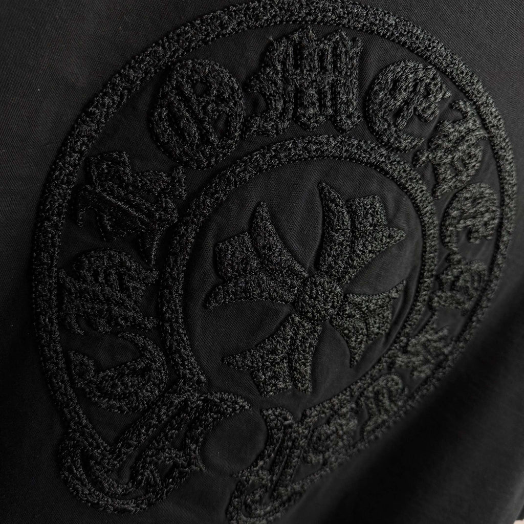 Black short-sleeve T-shirt with detailed embossed circular crest graphic