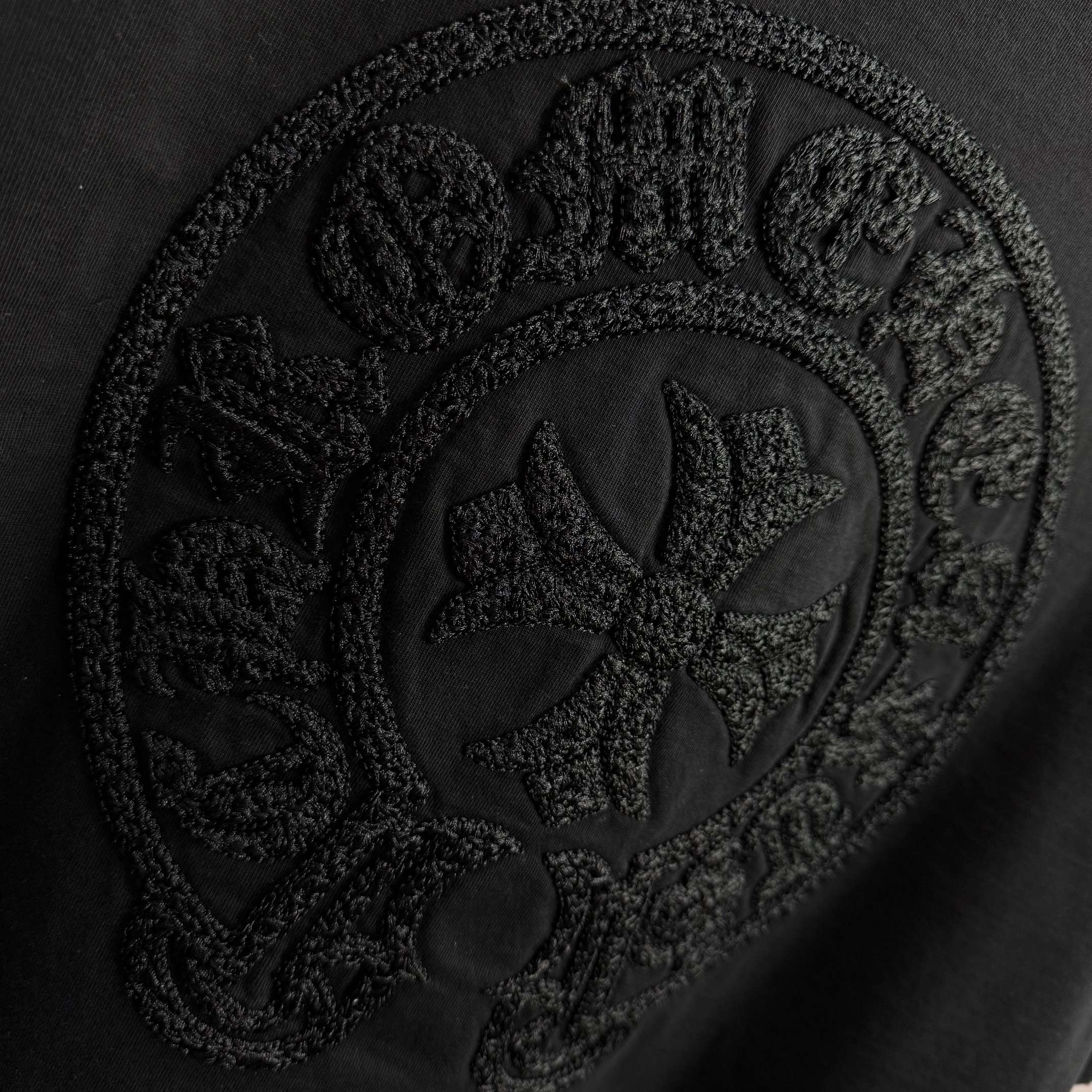 Black short-sleeve T-shirt with detailed embossed circular crest graphic