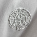 Light T-shirt with textured circular embroidered logo detail.