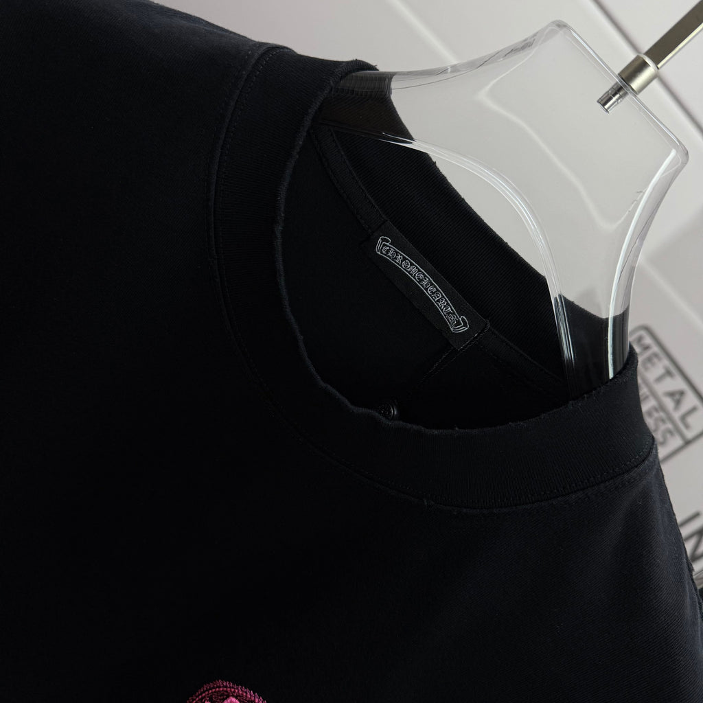 Black T-shirt neckline with inner collar label and pink embroidered chest icon