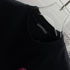 Black T-shirt neckline with inner collar label and pink embroidered chest icon