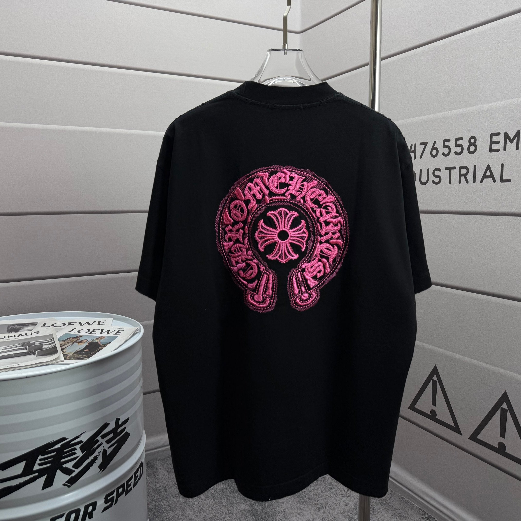 Black short-sleeve T-shirt with pink embroidered circular logo on chest