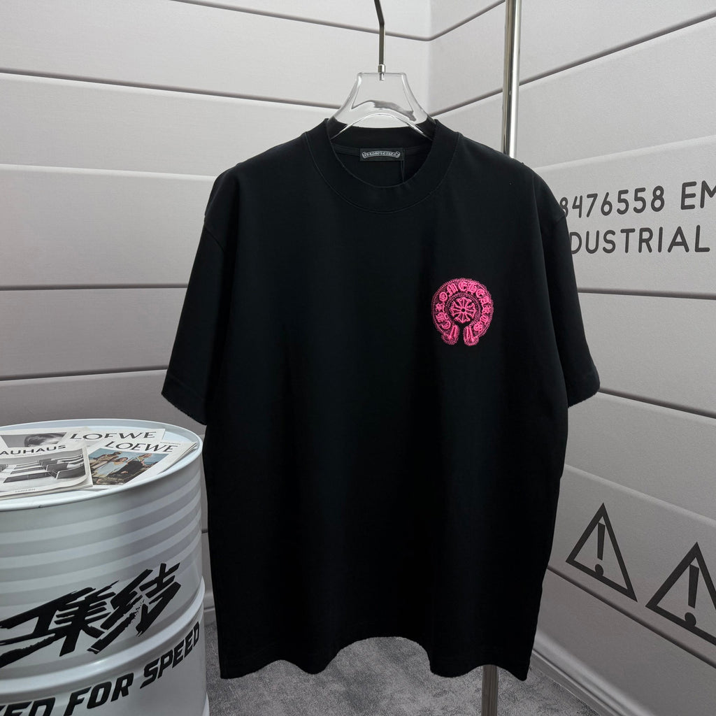 Black short-sleeve T-shirt with small pink embroidered circular emblem