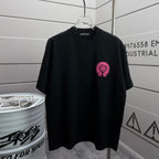 Black short-sleeve T-shirt with small pink embroidered circular emblem
