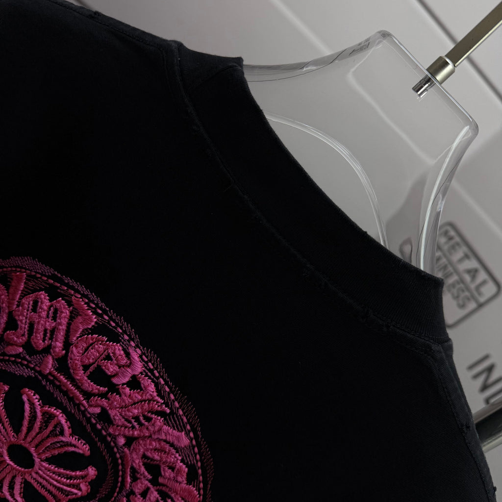 Black T-shirt shoulder and collar with partial pink embroidered graphic