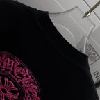 Black T-shirt shoulder and collar with partial pink embroidered graphic