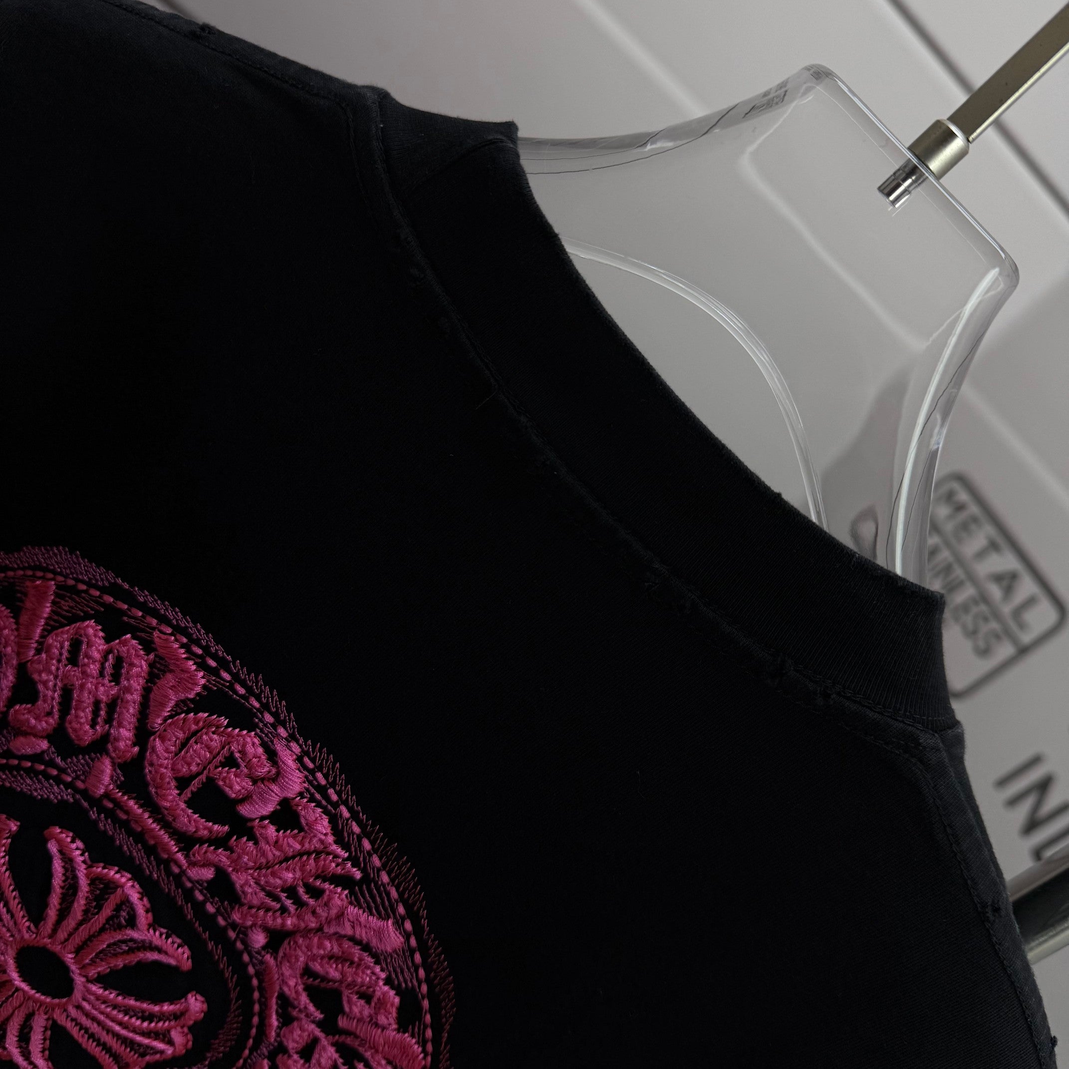 Black T-shirt shoulder and collar with partial pink embroidered graphic