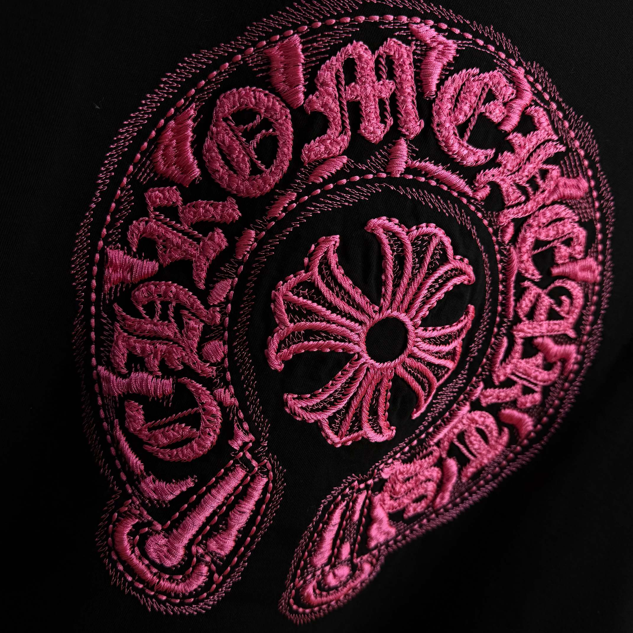 Black T-shirt with detailed pink embroidered circular emblem
