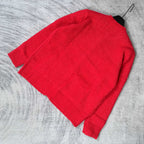 Red knit cardigan folded with crew neck and button placket visible