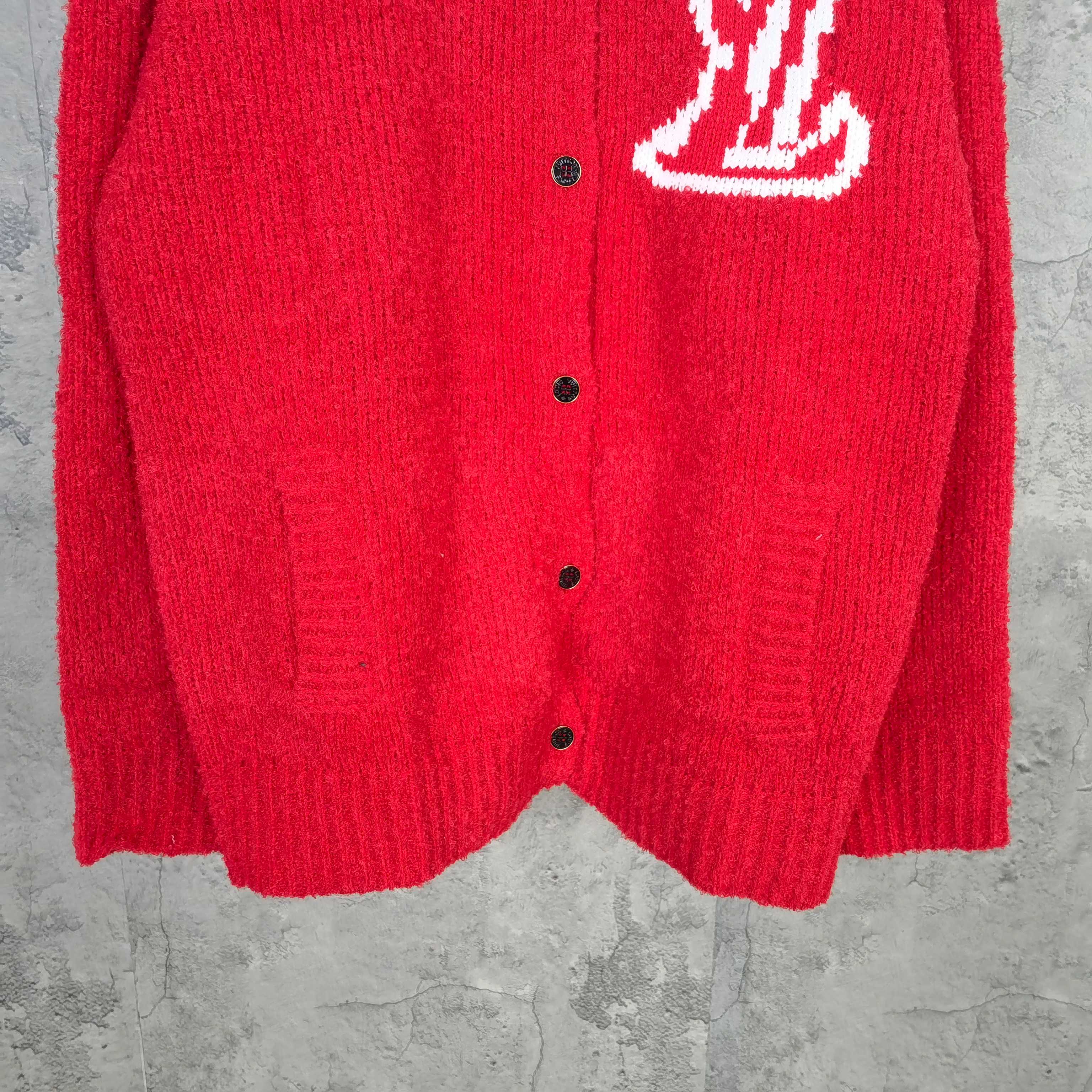 Red knit cardigan hem with button placket visible, straight silhouette