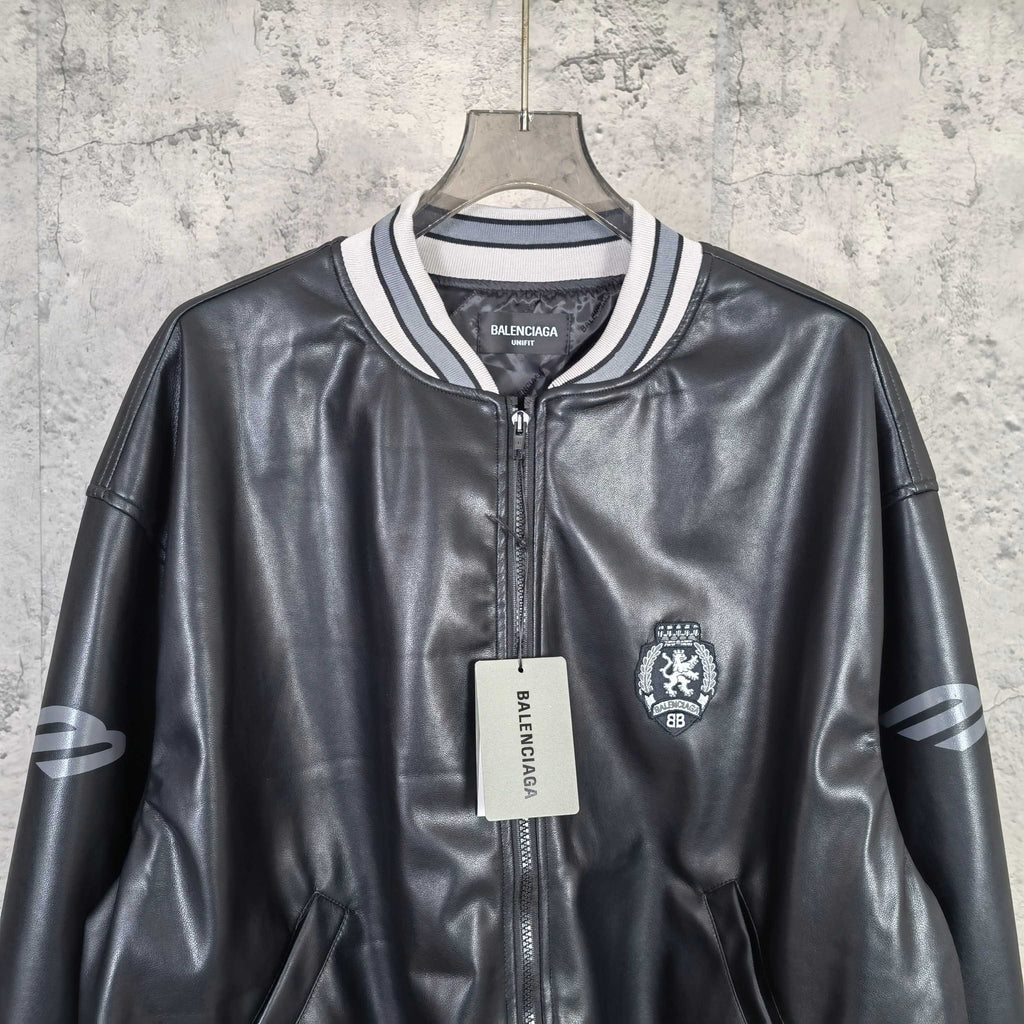 Balenciaga leather bomber jacket close-up with zipper, crest patch, and brand tag