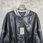 Balenciaga leather bomber jacket close-up with zipper, crest patch, and brand tag