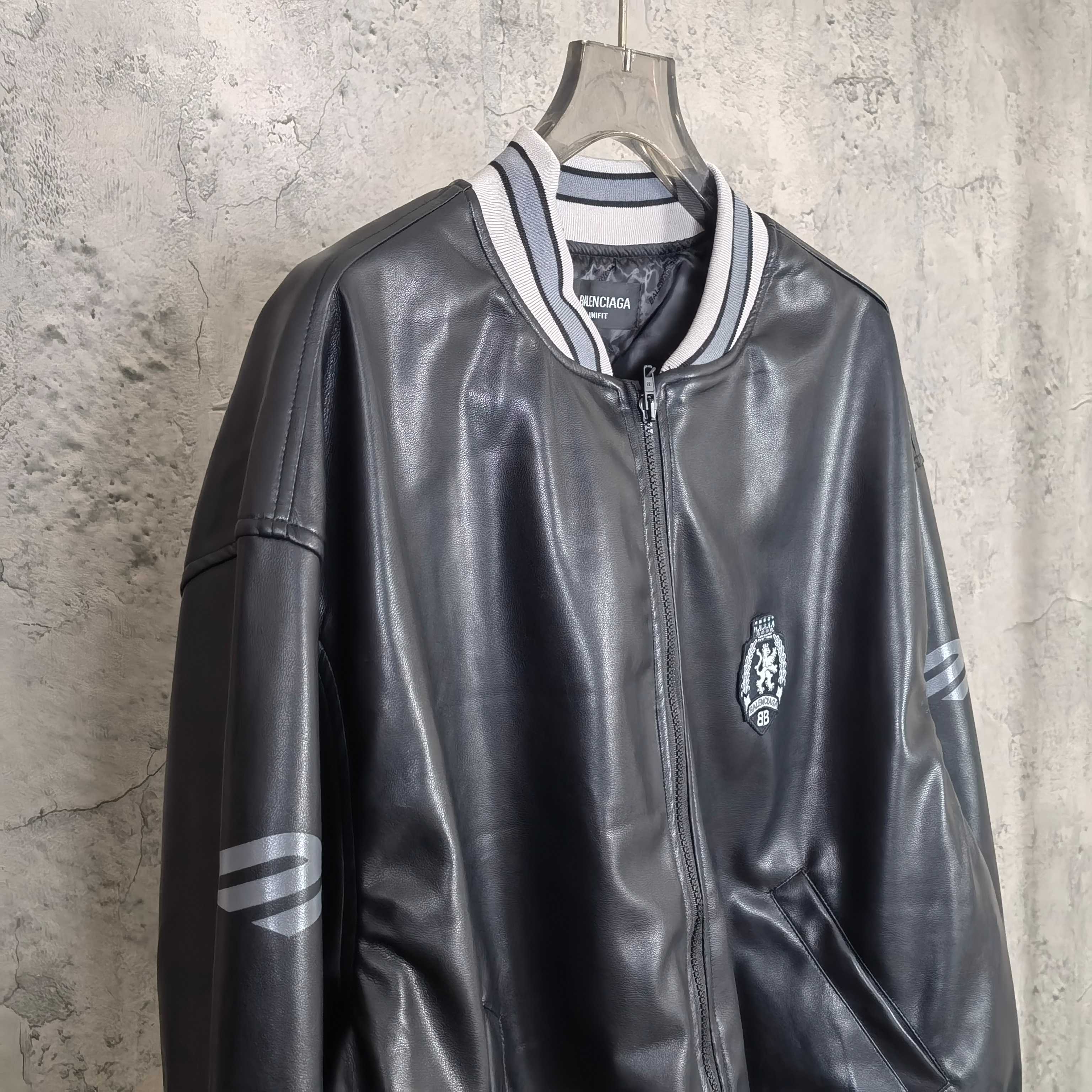 Balenciaga leather bomber jacket front view with zipper, crest patch, and sleeve stripes