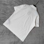 Balenciaga white polo shirt laid flat, short sleeves, collar and button edge visible