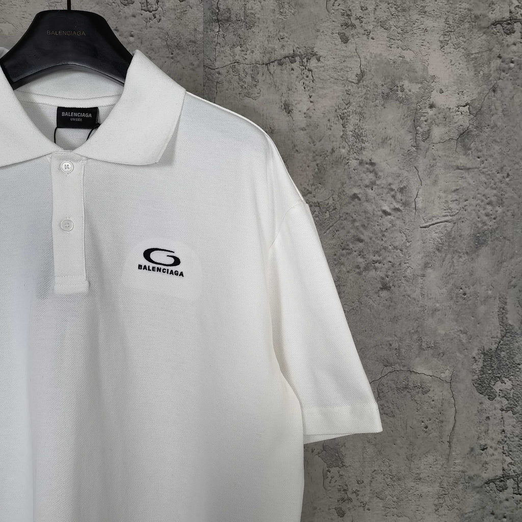 Balenciaga white polo shirt close-up with embroidered chest logo and button placket