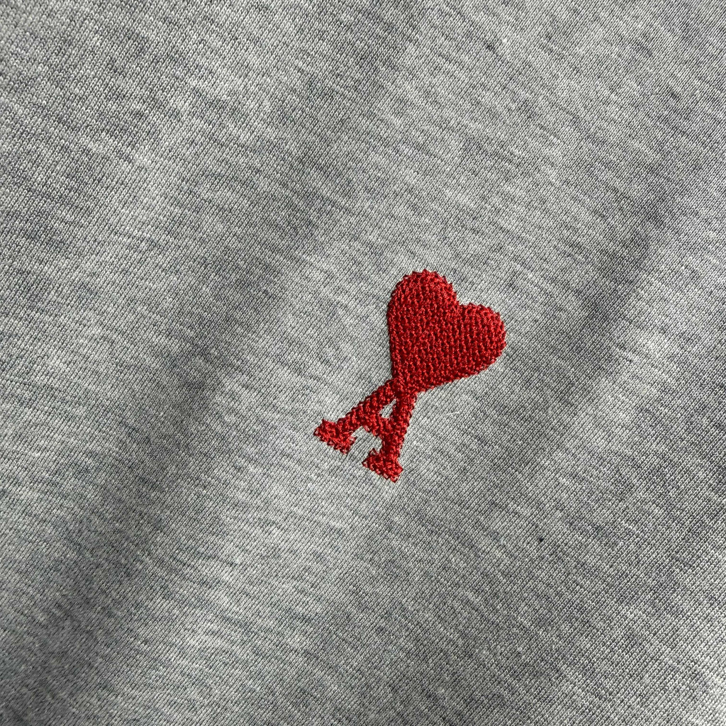 Heather gray T-shirt front with red heart-shaped logo and small red A detail.