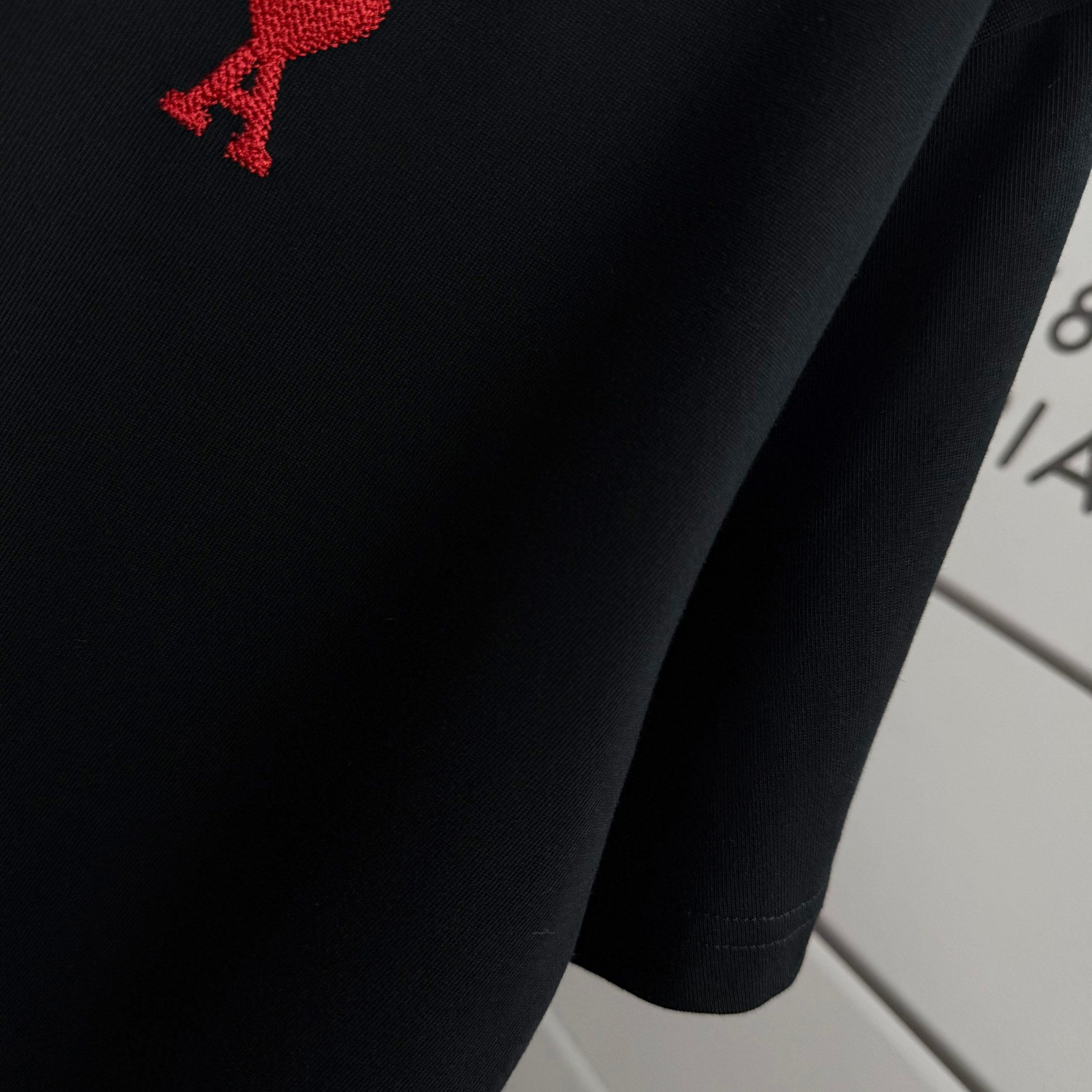 Black T-shirt front with partial red logo detail
