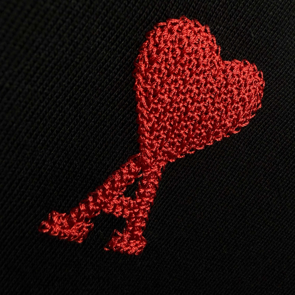Red heart-shaped logo embroidery on black textured T-shirt fabric