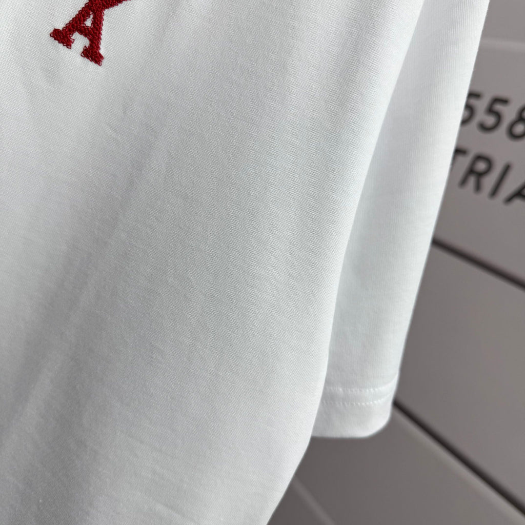 Amiri white T-shirt fabric close-up with partial red heart-and-A logo near shoulder