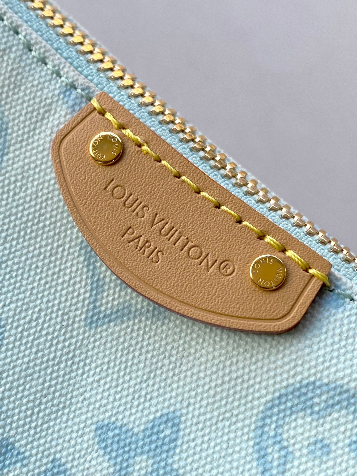 Louis Vuitton leather zipper pull tab on light blue monogram fabric with gold hardware