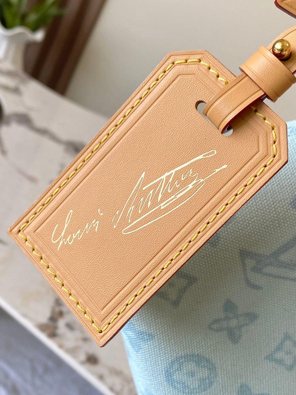 Louis Vuitton tan leather ID label patch on light blue monogram handbag strap