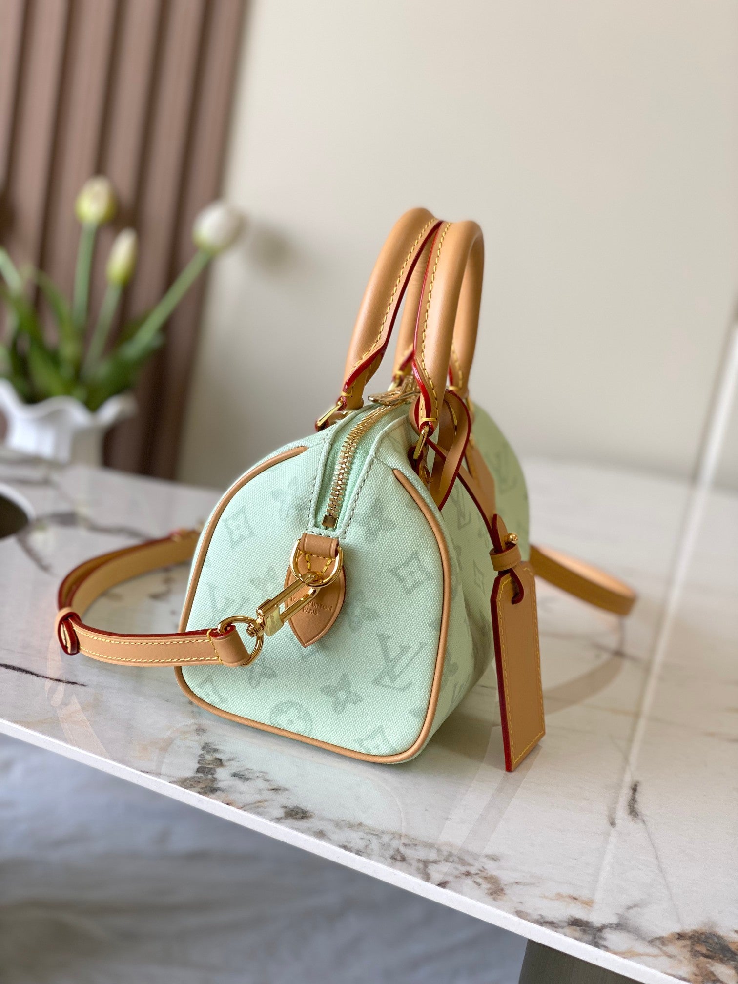 Mint green handbag with tan leather straps, gold clasp, and monogram pattern