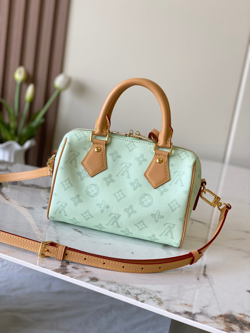 Mint green Louis Vuitton mini handbag with tan handles and adjustable crossbody strap