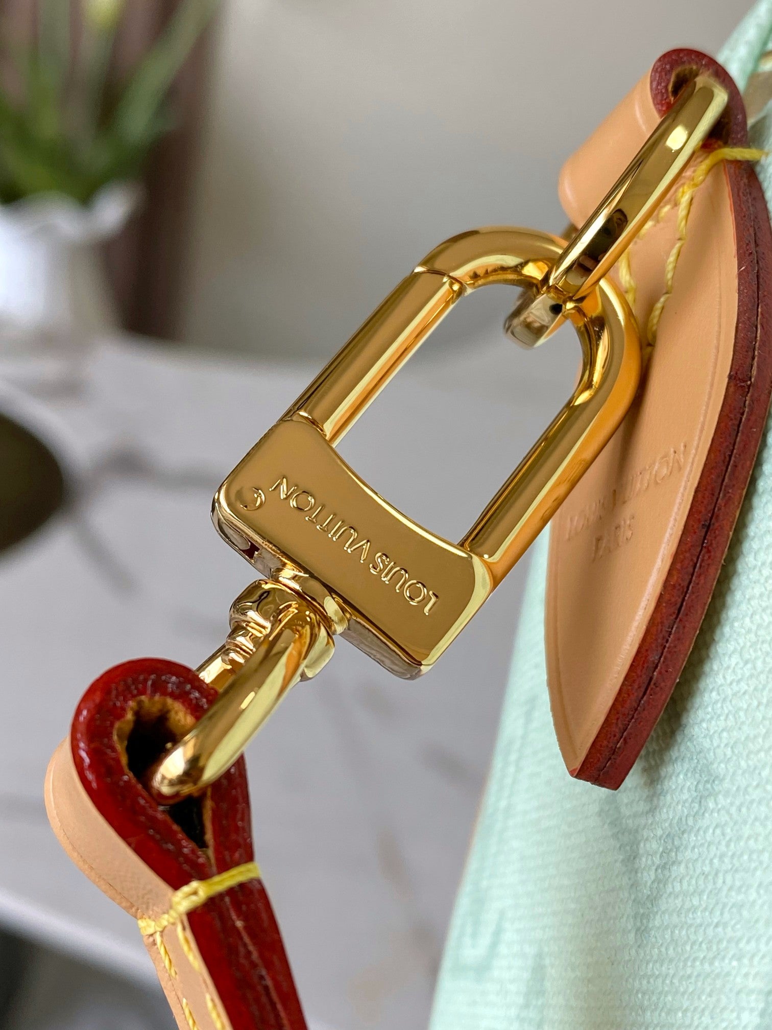 Gold tone padlock charm and tan leather strap on a mint green handbag