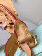 Tan leather strap detail with red lining and gold buckle on a mint green handbag
