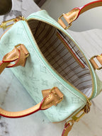 Mint green handbag open with striped interior and gold zipper track