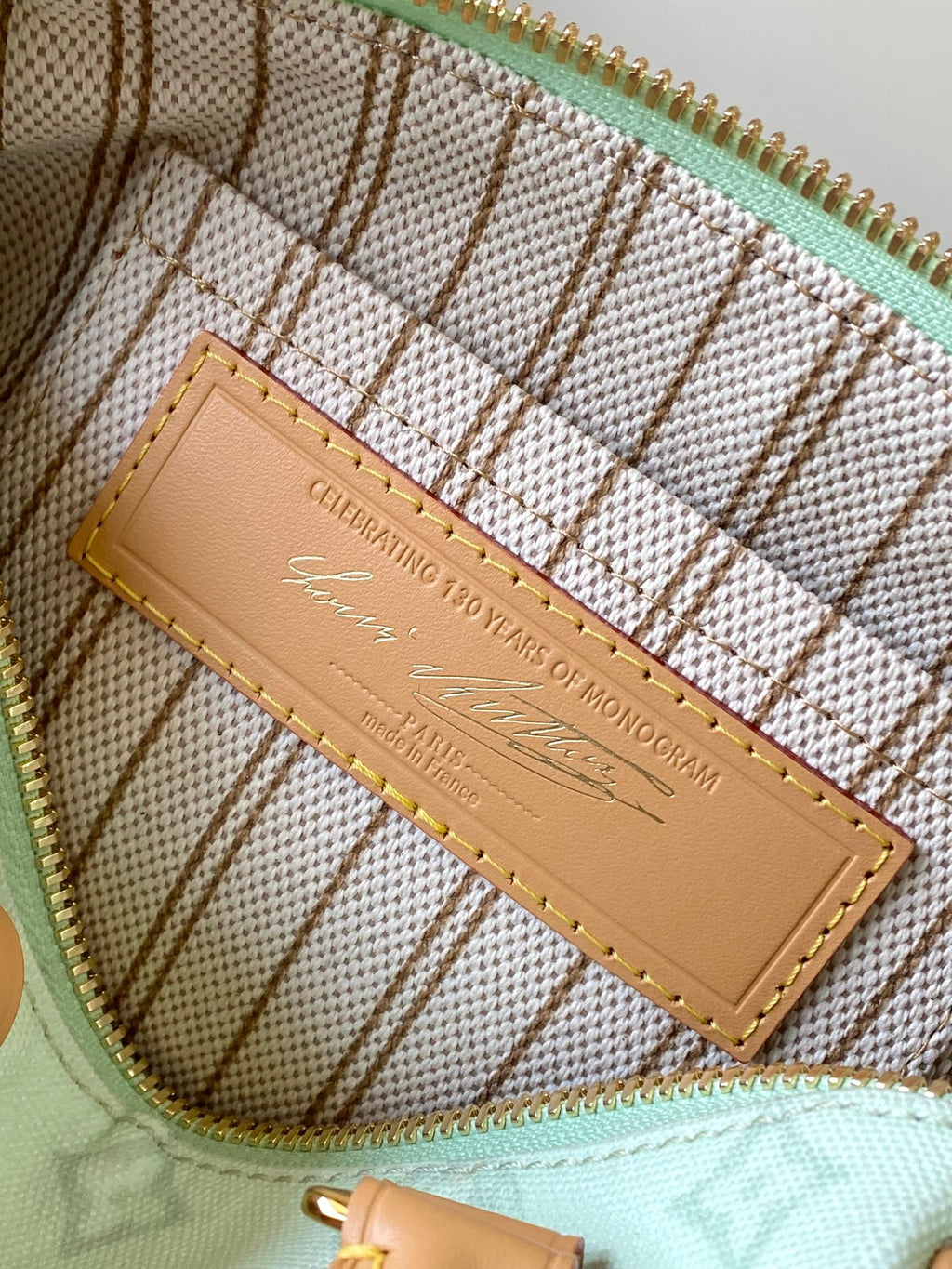 Mint green handbag interior with tan brand plate and gold stitching detail