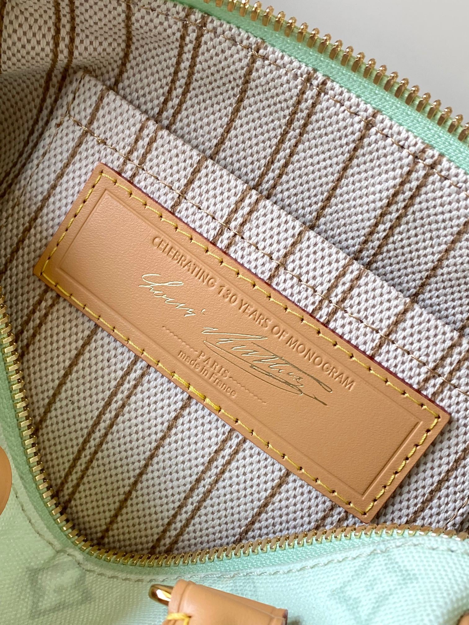 Mint green handbag interior with tan brand plate and gold stitching detail
