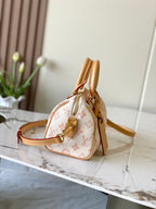 Monogram handbag with tan leather trim and adjustable crossbody strap, gold hardware