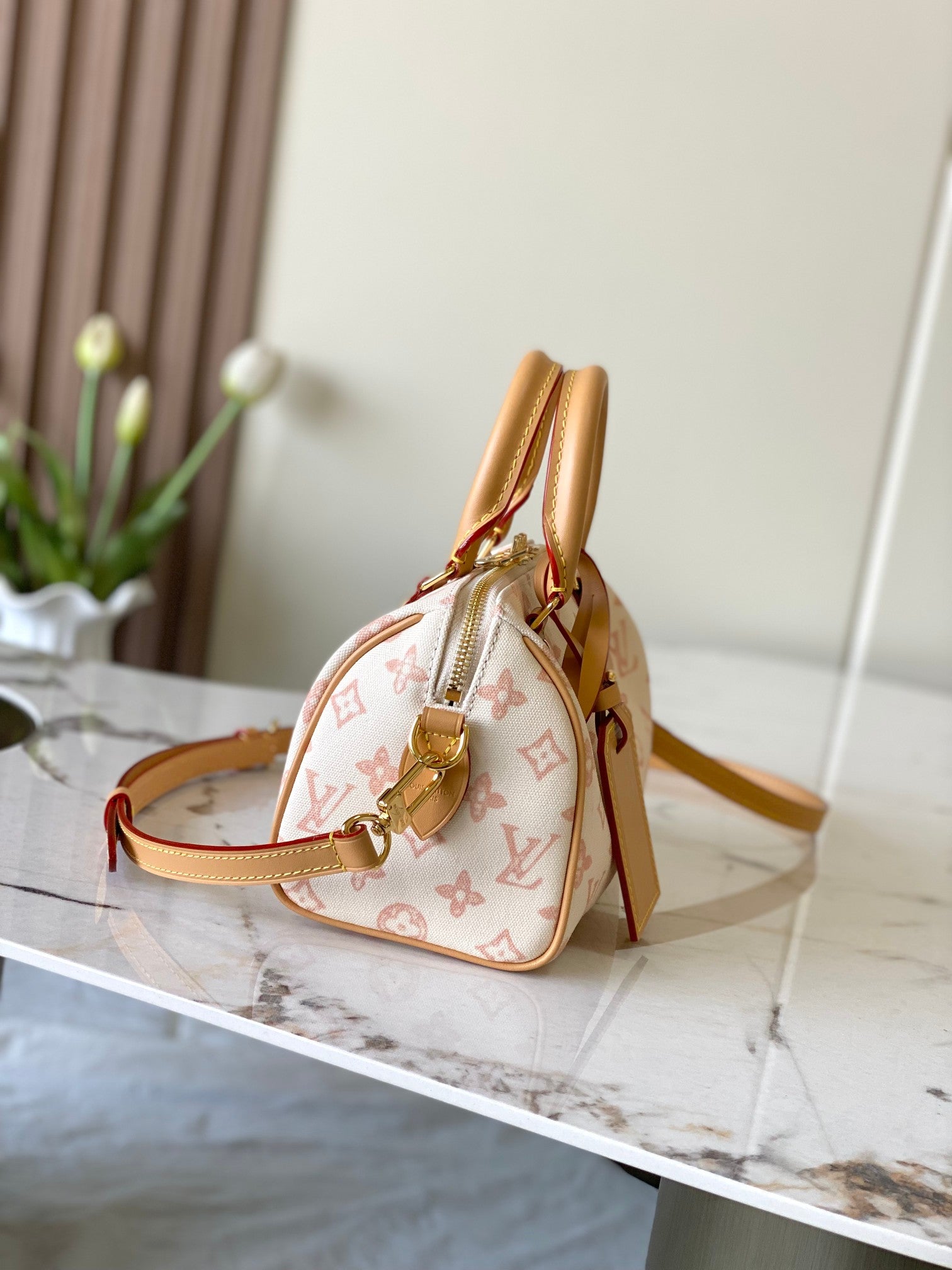 Monogram handbag with tan leather trim and adjustable crossbody strap, gold hardware