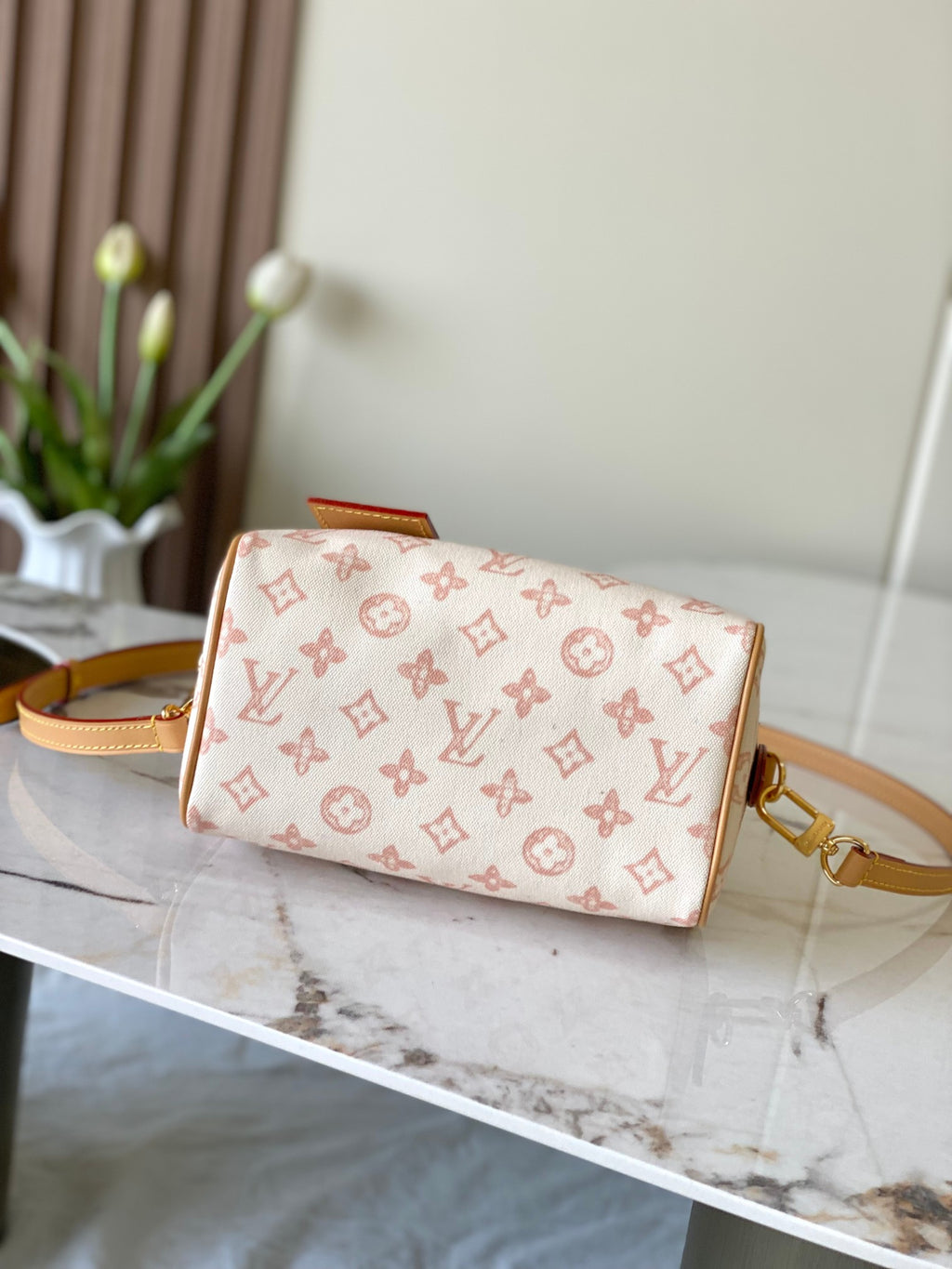 Monogram wristlet bag with tan leather trim and gold zipper, structured top