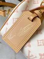 Leather nameplate detail on monogram handbag, tan panel with embossed signature