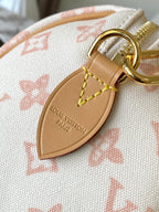Leather luggage-tag charm on monogram handbag with gold ring and embossed logo