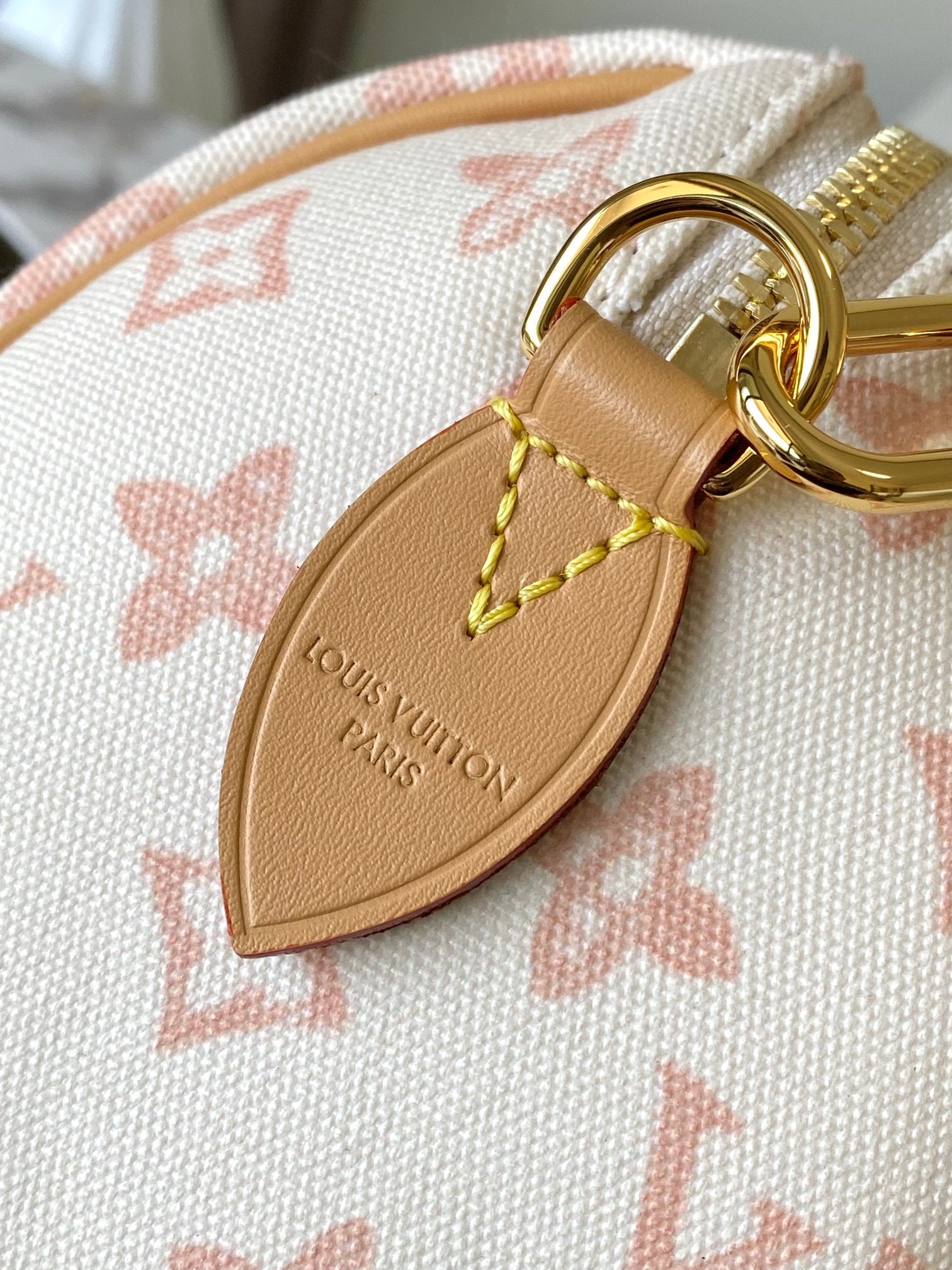 Leather luggage-tag charm on monogram handbag with gold ring and embossed logo