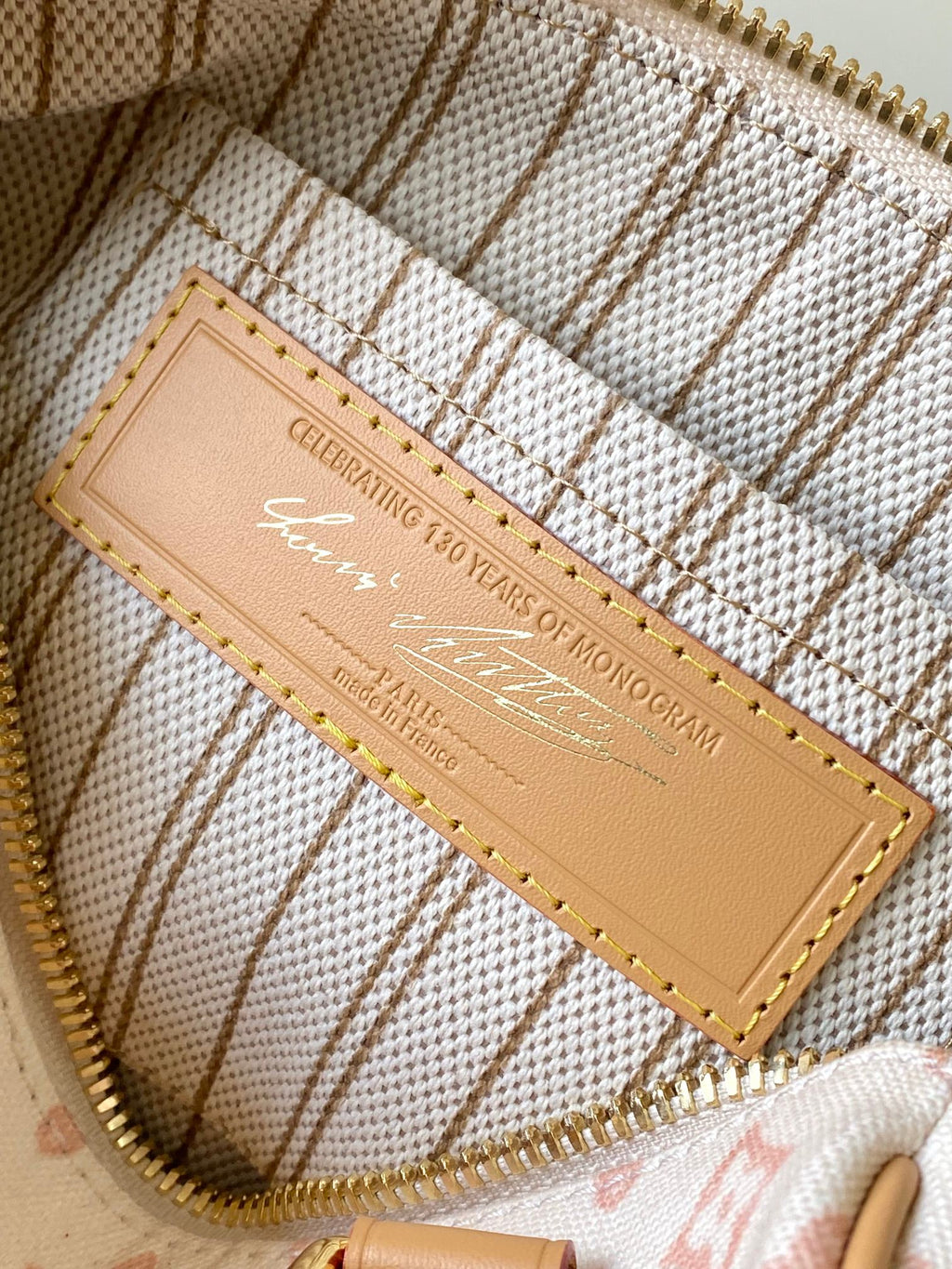 Monogram handbag interior authenticity label on tan leather patch with gold stitching