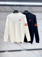 Pair of knit sweaters on hangers: white and dark navy, crewneck with red chest crest