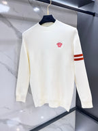 White knit sweater from front, crewneck, red crest on chest, orange striped sleeve cuff