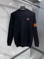 Dark navy knit sweater, crewneck, small red crest on chest, orange striped sleeve cuff