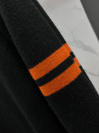 Black knit sweater sleeve with orange and black striped cuff detail