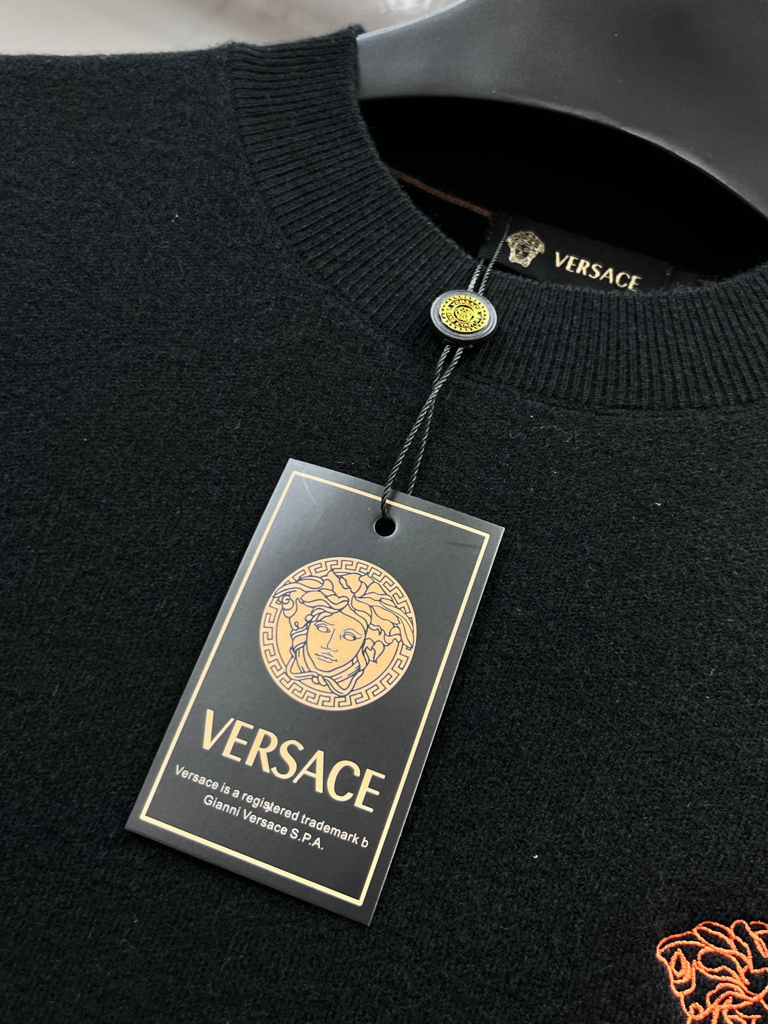 Versace knit sweater neckline with VERSACE label and attached hang tag