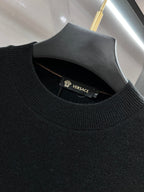 Black knit sweater neckline with ribbed crew collar and hanging inner brand label