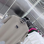 Light gray crewneck T-shirt on hanger with navy chest logo