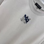 Light gray crewneck T-shirt close-up, small navy logo on chest