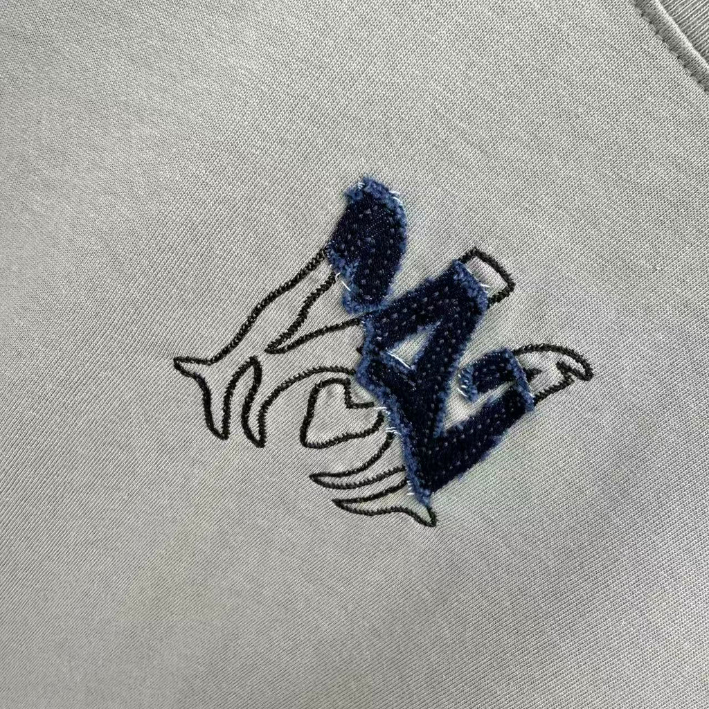 Light gray crewneck T-shirt close-up of navy logo embroidery